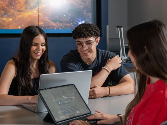 two students smiling at a laptop